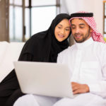 lovely arabian couple using laptop at home